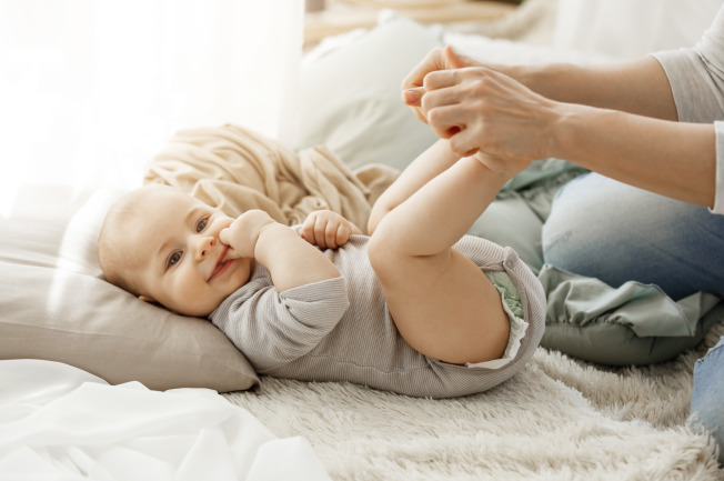 Khi con nằm ngửa, mẹ có thể massage 2 chân cho bé kết hợp di chuyển chân