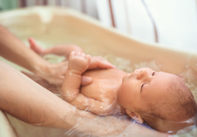 Để giúp bé thư giãn và thoải mái trong khi tắm, hãy đặt một tay của mẹ nhẹ nhàng lên bụng của bé.