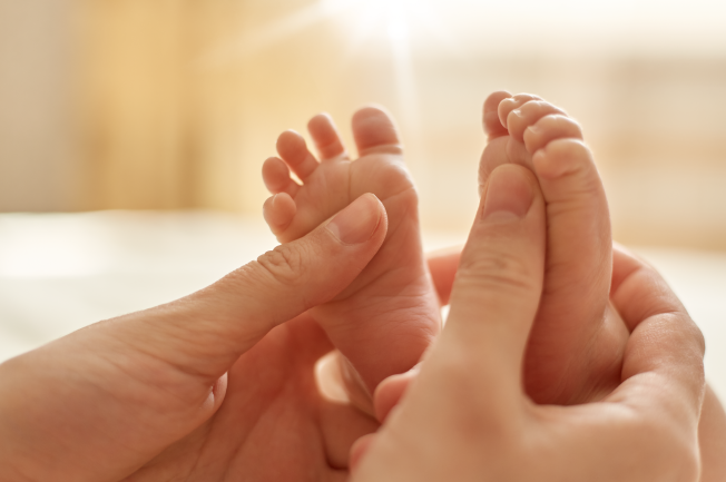 Mẹ có thể mát-xa cho con bằng cách nhịp nhàng di chuyển hai và lăn tay, chân bé giữa hai bàn tay của mẹ