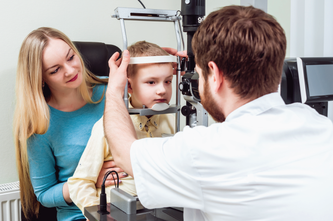 Hình ảnh một em bé được bác sĩ khám tật khúc xạ mắt 