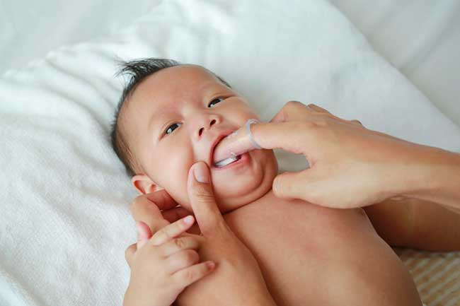 Massage vị trí mọc răng có thể giúp bé cải thiện tình trạng bú bình hay nhai