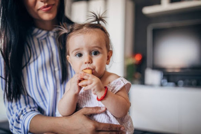 Mẹ cho bé tự ăn để luyện tập đôi tay tinh tế hoặc mẹ cầm để kiểm soát lượng bánh bé ăn