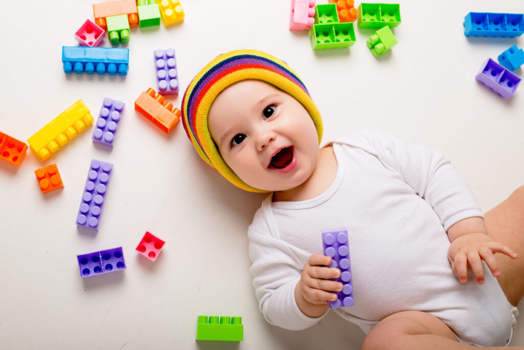 baby boy playing with multi colored constructor white wall 1 1