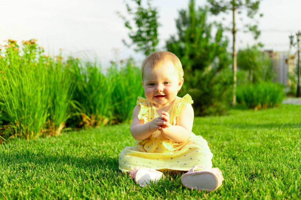 happy baby girl plays walks green lawn summer park