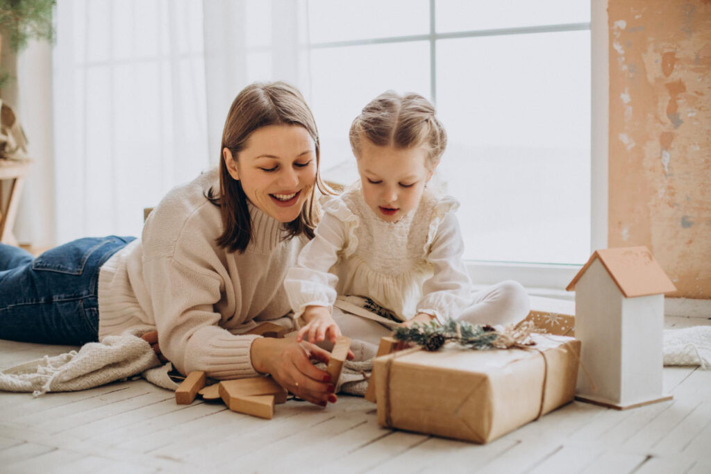 mother with her daughter packing christmas presents having fun